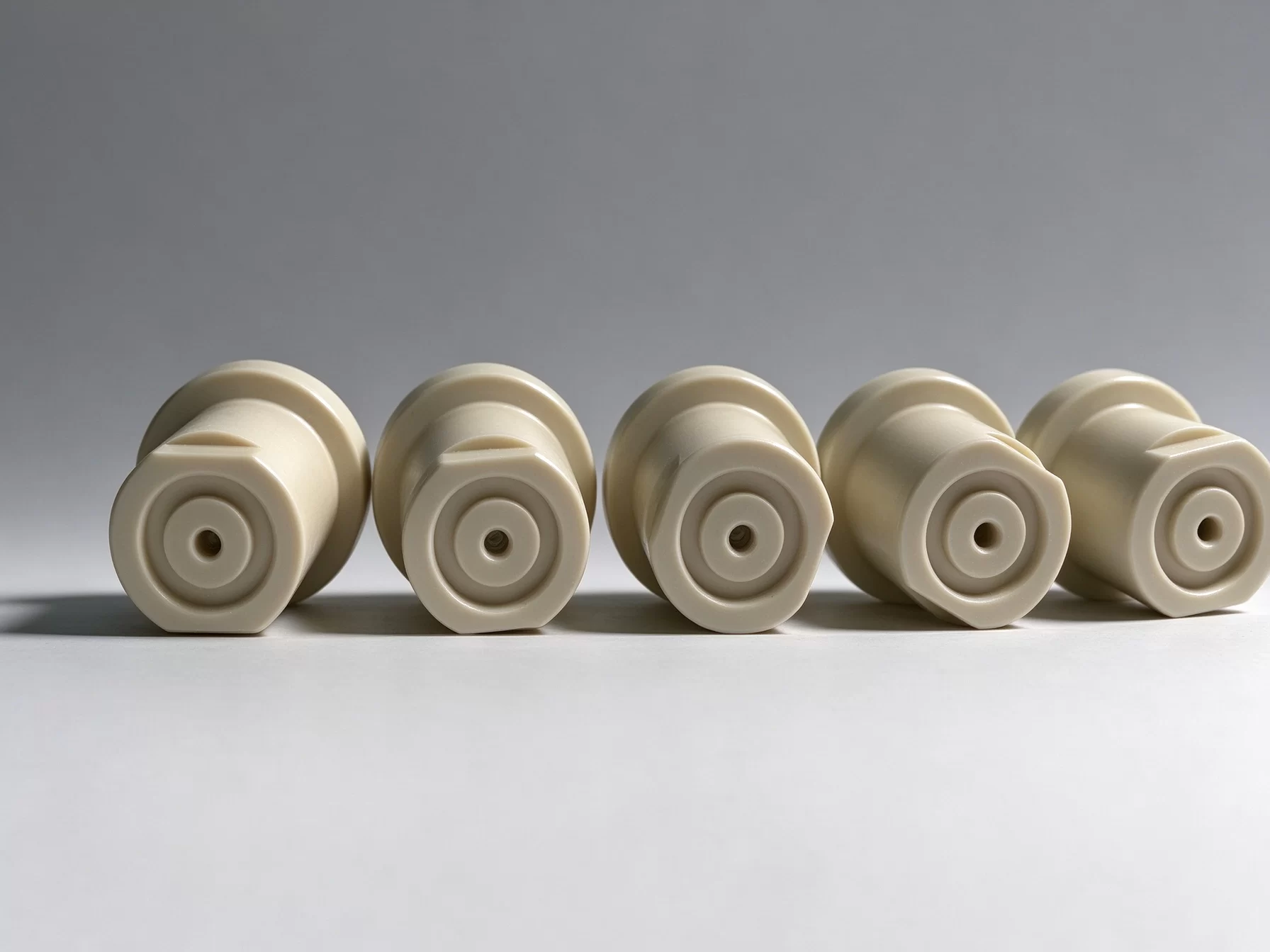 PEEK rod stock CNC machined stepped plastic parts CNC machined beige PEEK stepped components, manufactured from high-performance plastic rod stock, shallow grey gradient background
